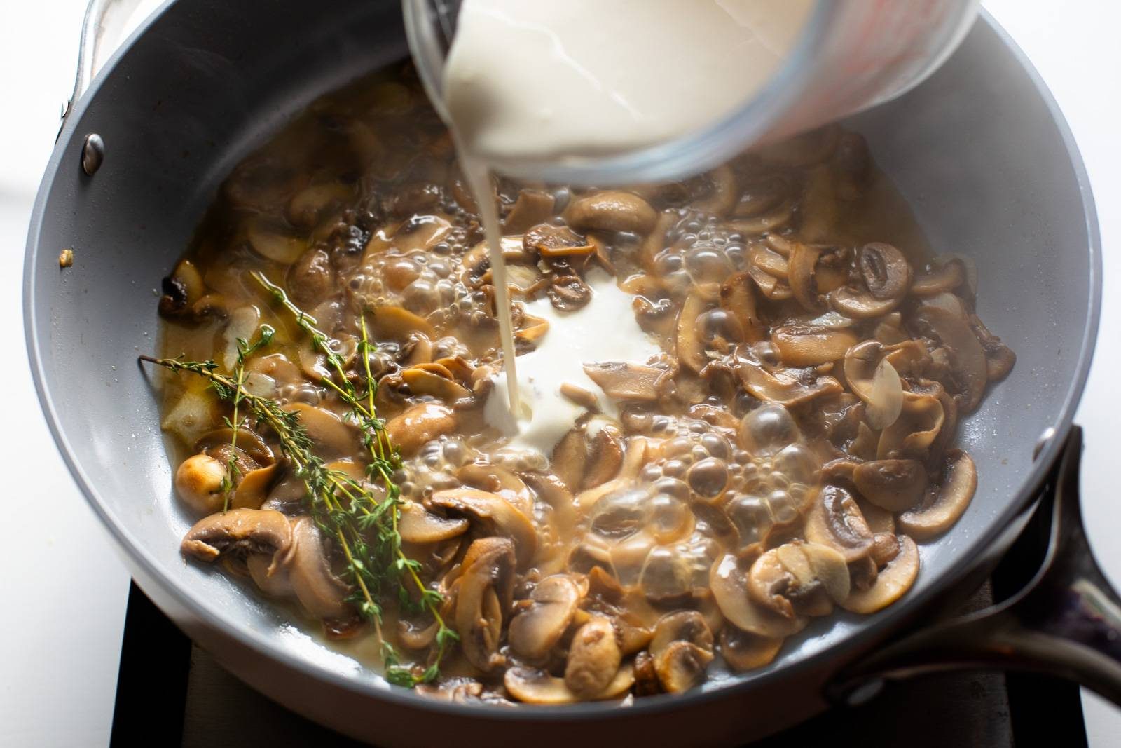 Adding cream to mushroom sauce.