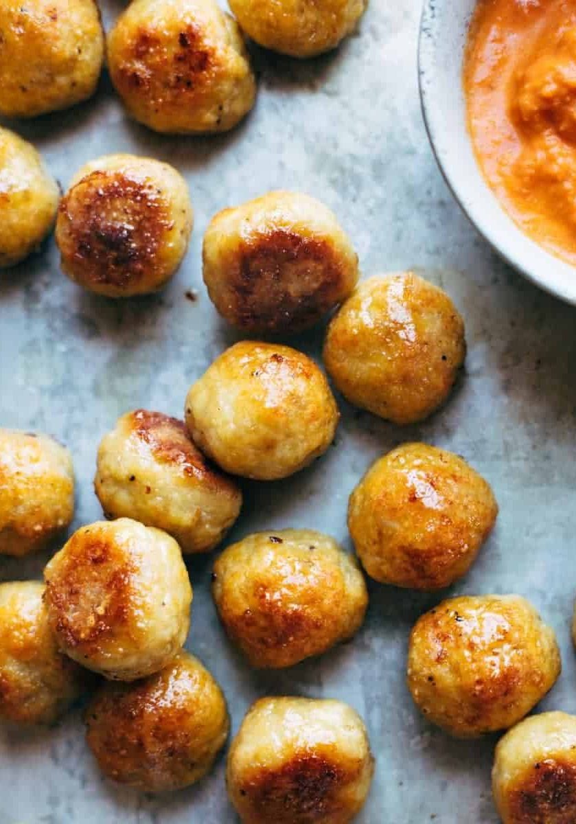 Baked Chicken Meatballs on a sheet pan with sauce.