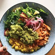 Chicken bowls with yellow rice, greens, onions, and cilantro pesto.