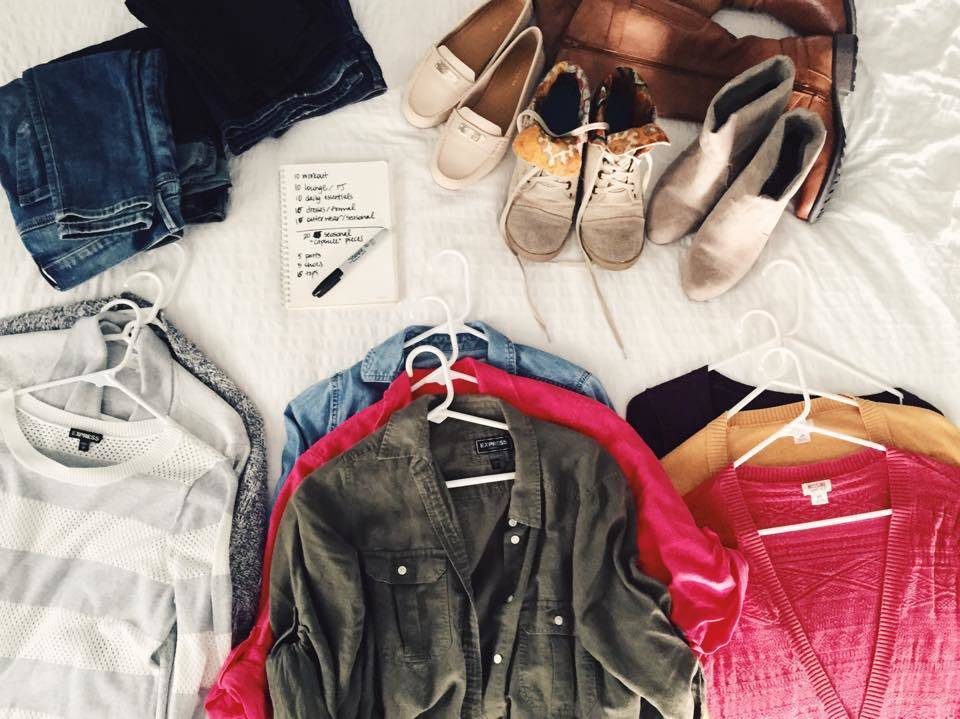 Shirts, scarf, a notebook and a pen on a bed.