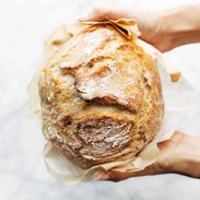 White hands holding homemade no knead bread.