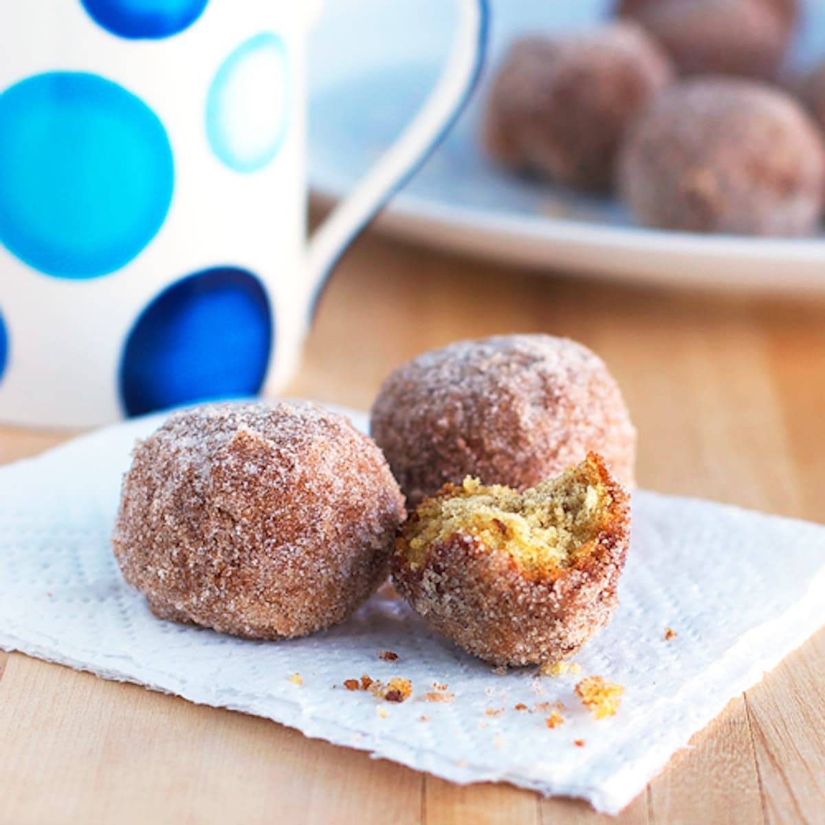 Cinnamon sugar donut balls with crumbs on a napkin.