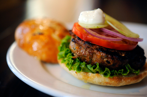 Kouzzina lamb burger, dressed with olives and feta, with a side of sweet potato fries