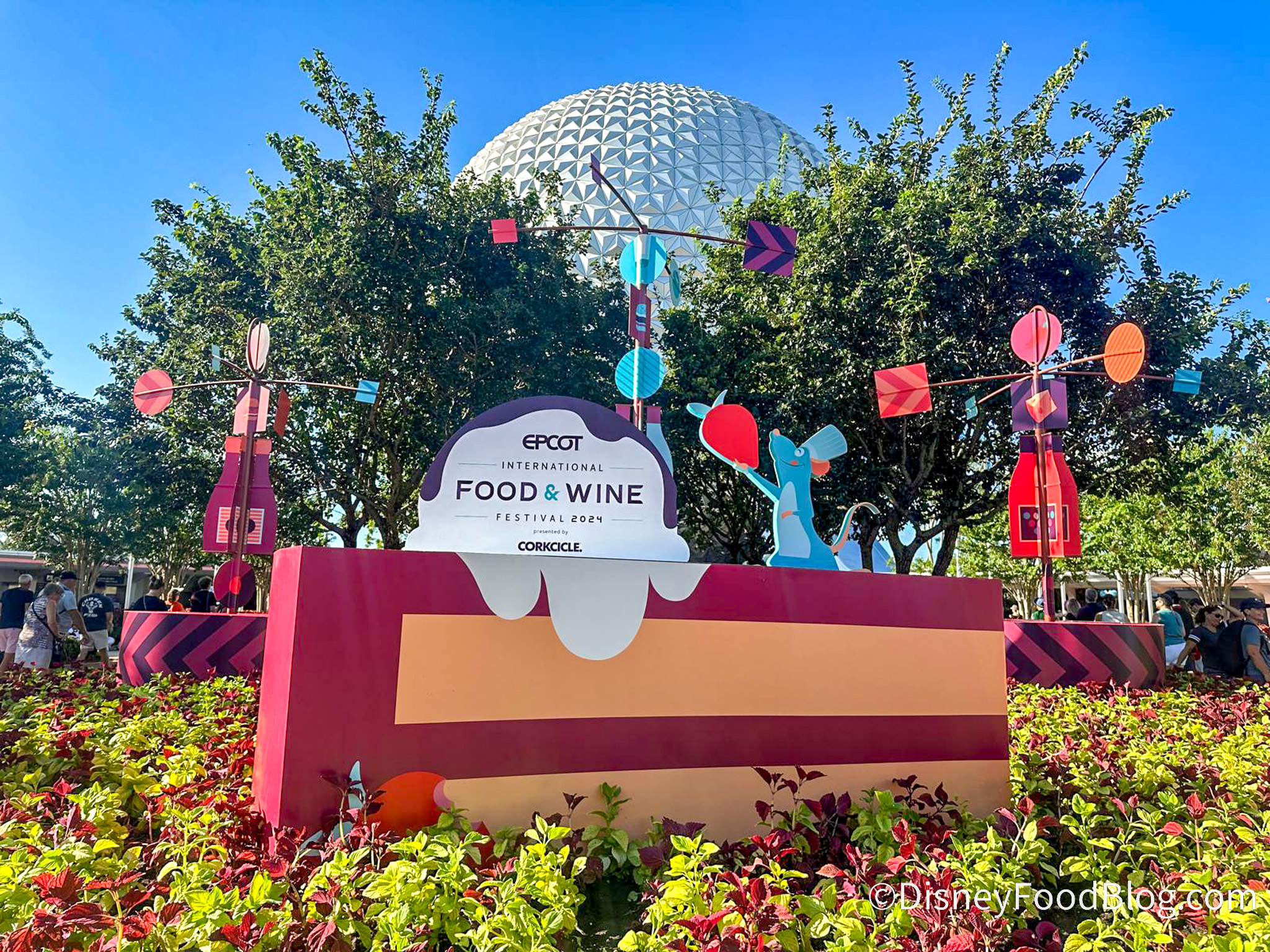 food and wine sign with large slice of cake with remy the rat in blue on top. spaceship earth in back.