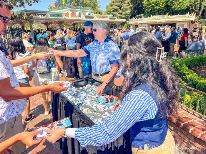cast members hand out maps with lots of crowds behind