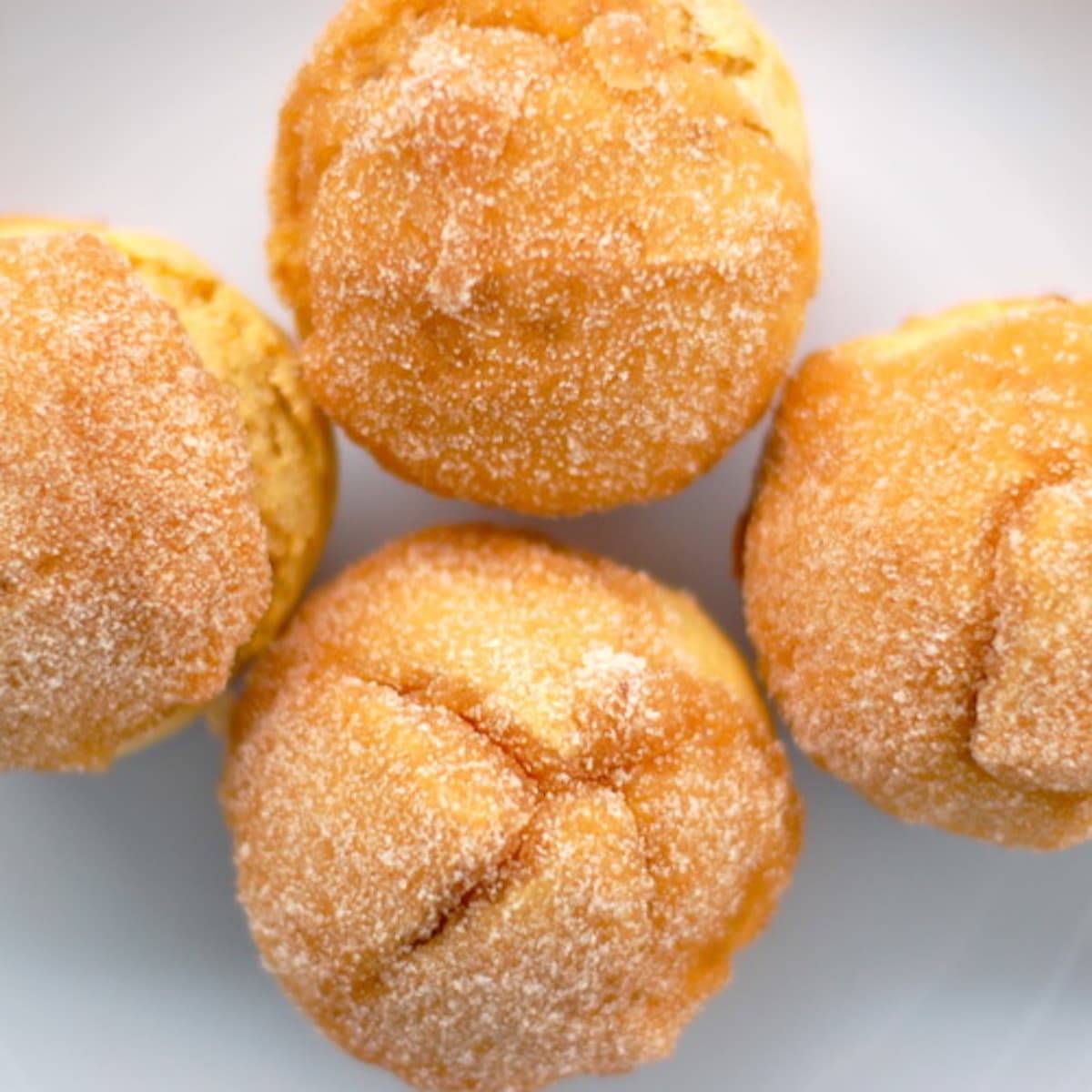 Four sugar-dusted sweet potato muffins.