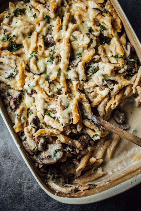 Healthy Mushroom Alfredo Pasta Bake in a dish with a wooden spoon.